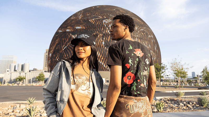 Two individuals stand in front of the Sphere, showcasing its impressive architecture and scale.